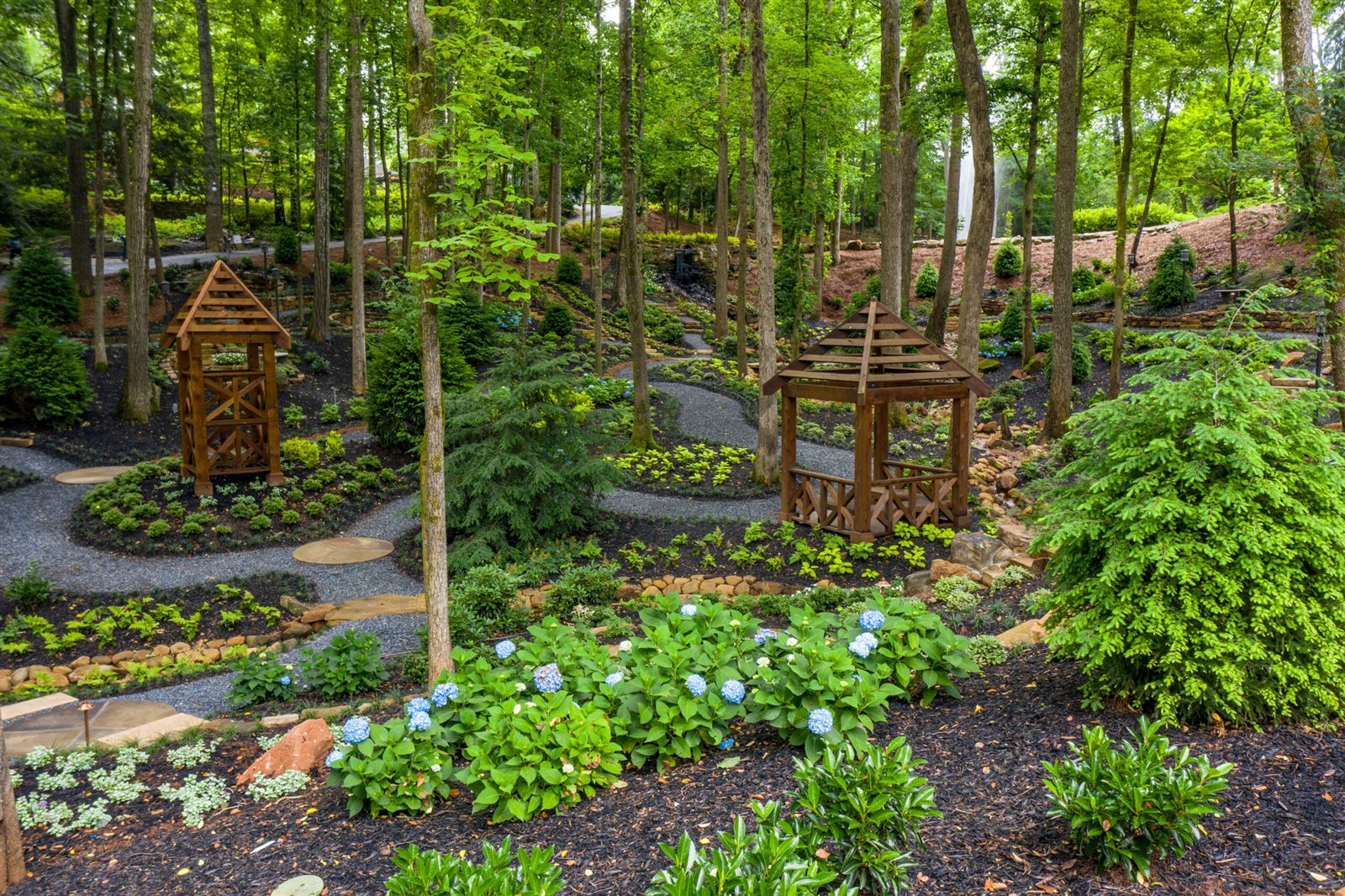 Custom landscape design with layered plantings and defined gravel paths installed by Varro