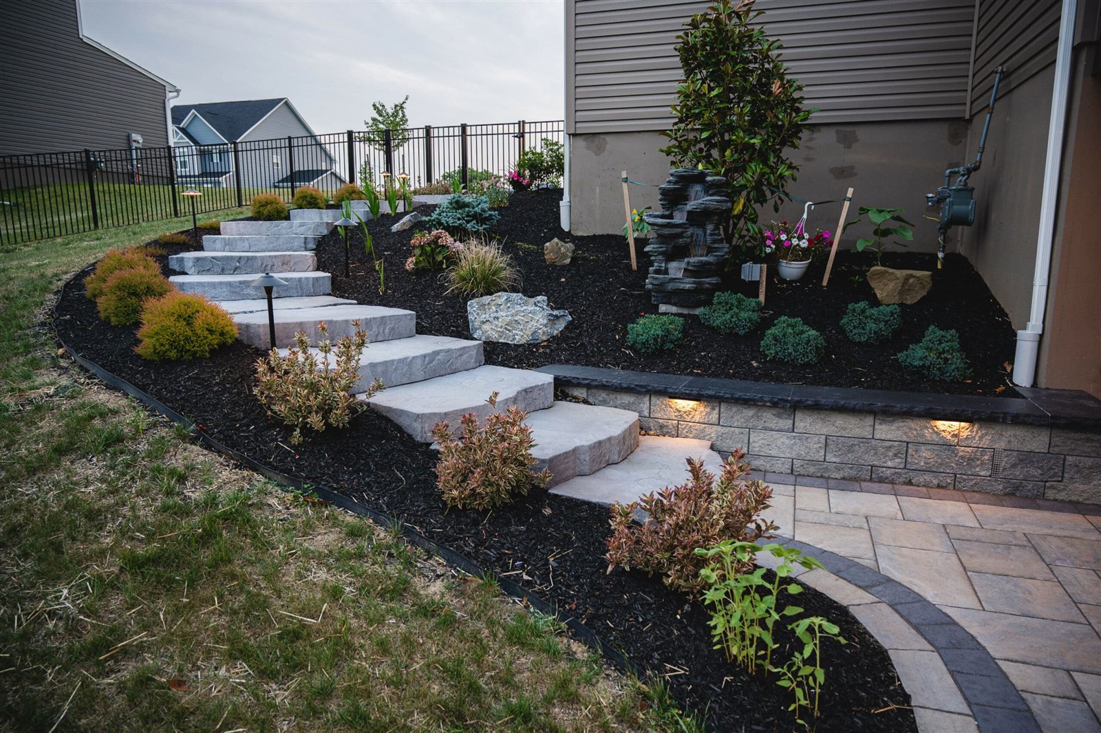 Stone steps, fresh mulch beds and landscape lighting installed on a sloped yard
