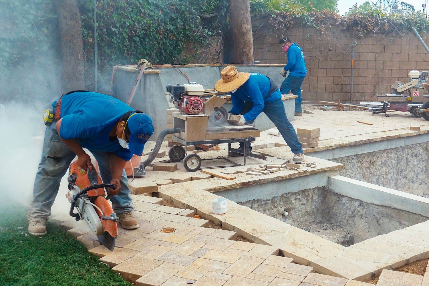 Crew cutting and laying pavers during an outdoor living installation
